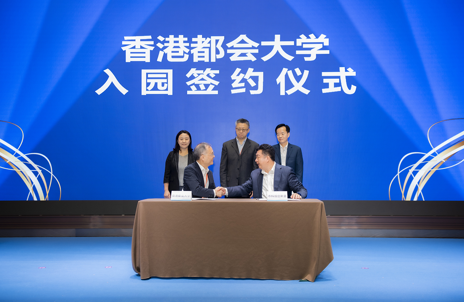 Deputy Director Lou Yanfeng of the Science, Technology and Innovation Commission of Shenzhen Municipality (front row, right) and HKMU President Prof. Paul Lam Kwan-sing (front row, left) express gratitude by shaking hands after signing the Admission Agreement.